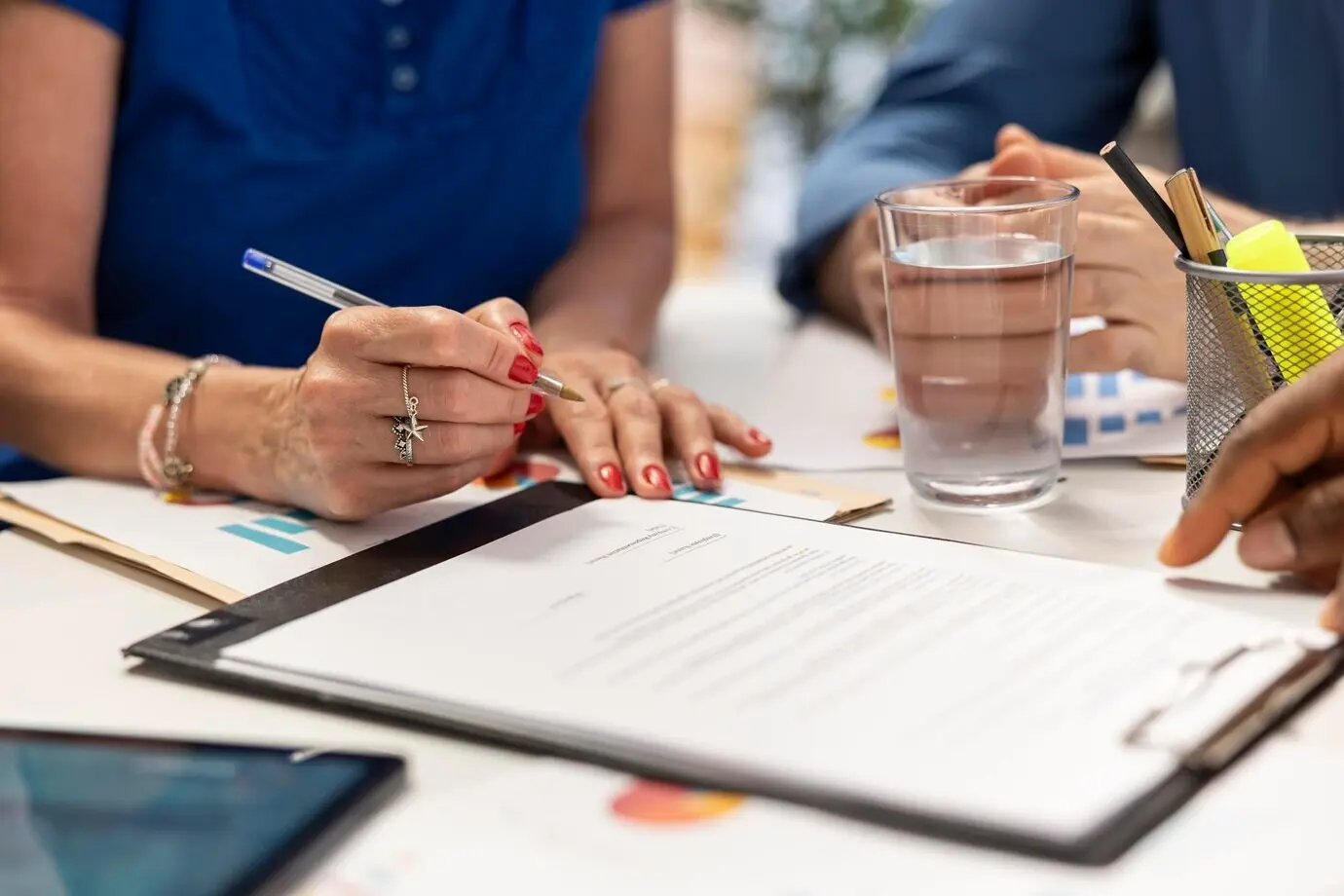 Mujer mayor firmando el nuevo contrato del plan de jubilación en una reunión.